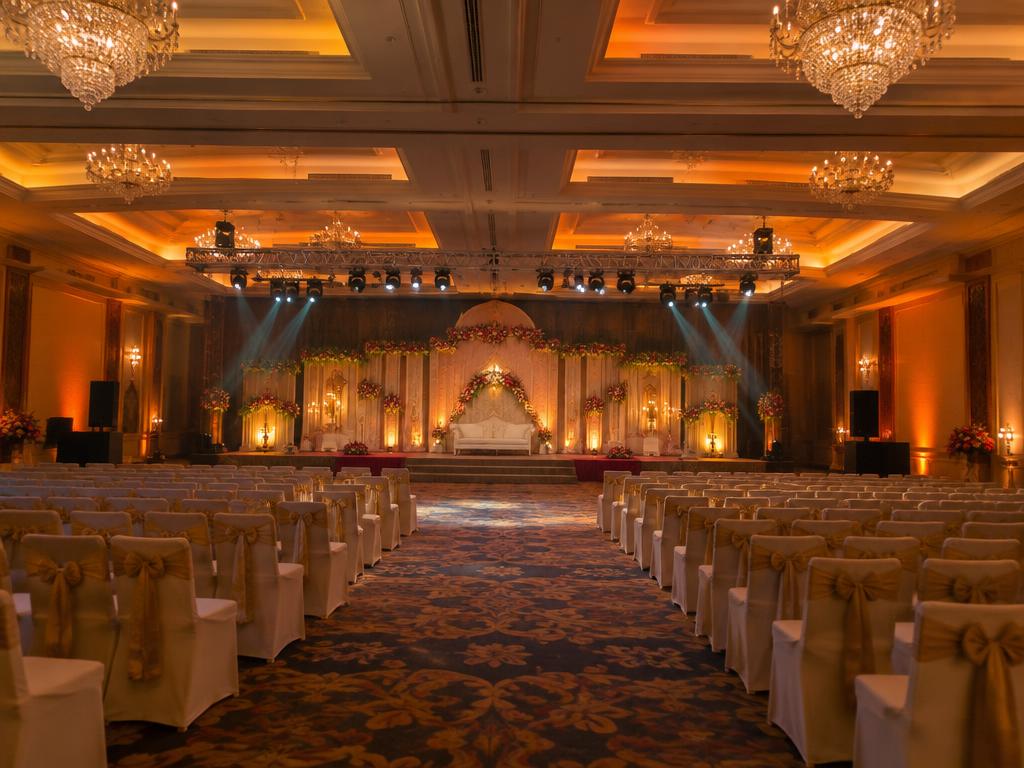 Banquet hall with stage lighting, warm uplighting and chandeliers